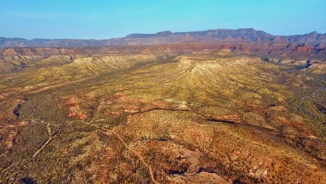 High-Rising-Aerial-View-of-Barren-Open-Desert-with-Dramatic-Mountain-Range-Background