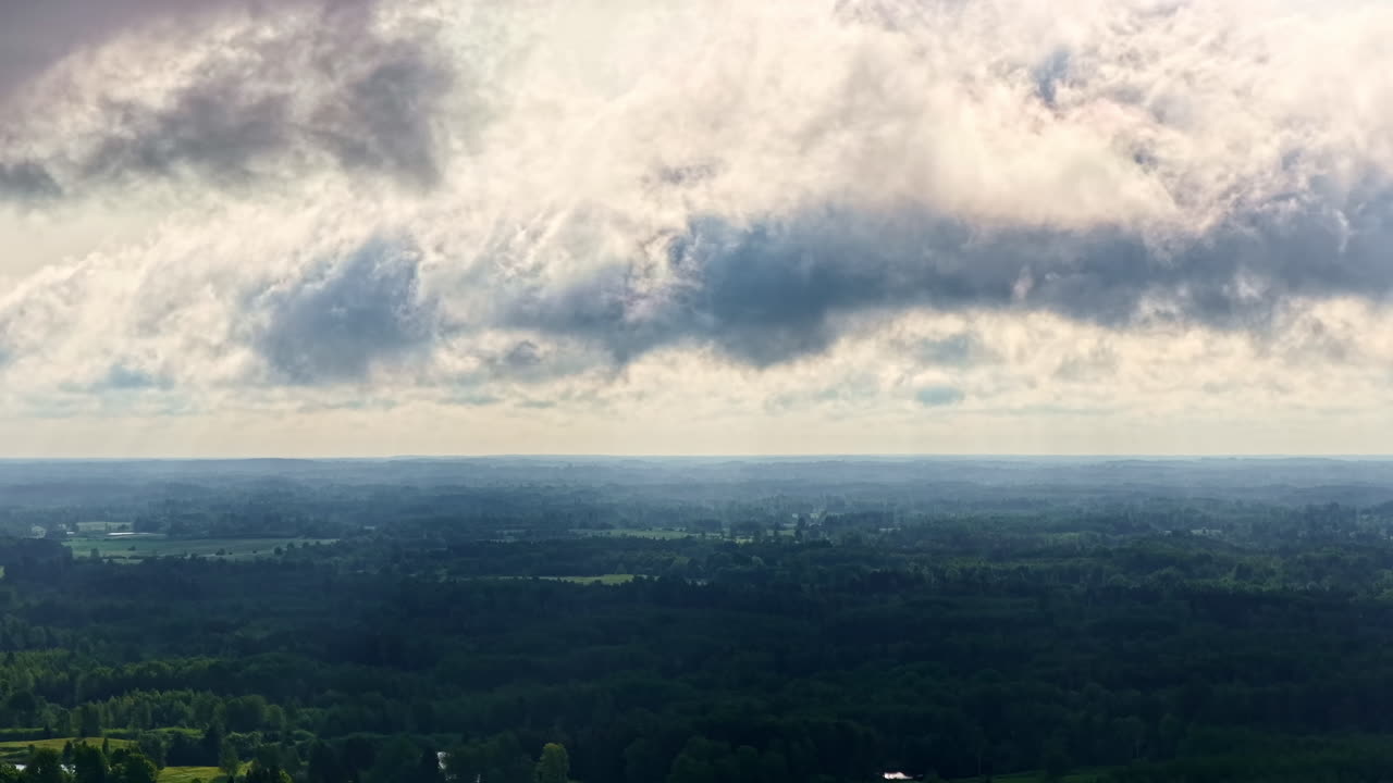 Dramatic cloud formations over vast green landscape under daylight sky