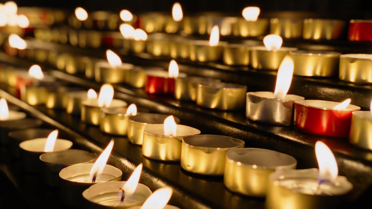 Portacandele tealight dorati che tremolano vicini su una sporgenza metallica.