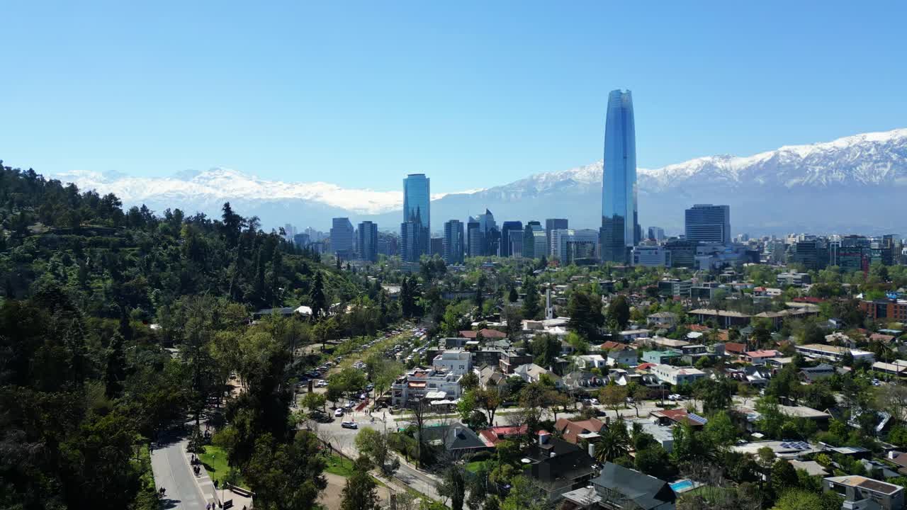 Santiago, Chile drone aerial pan over Costanera Center and city skyline with snow-capped Andes in clear midday light