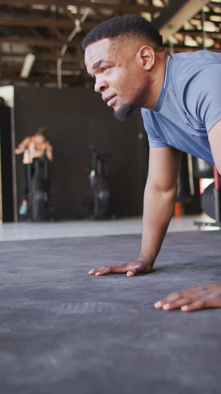 video vertical de mujer y hombre diversos y en forma haciendo flexiones en el gimnasio