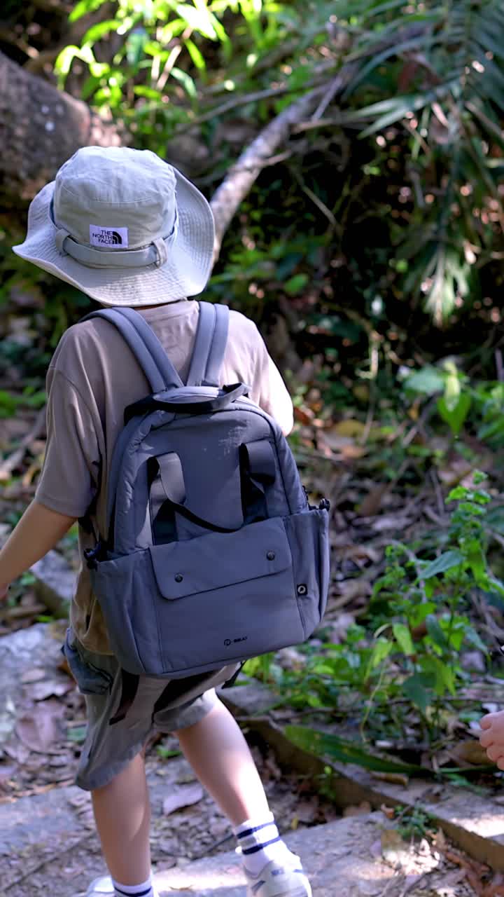 Rear view of two children with backpacks walking down stone steps on a forest trail