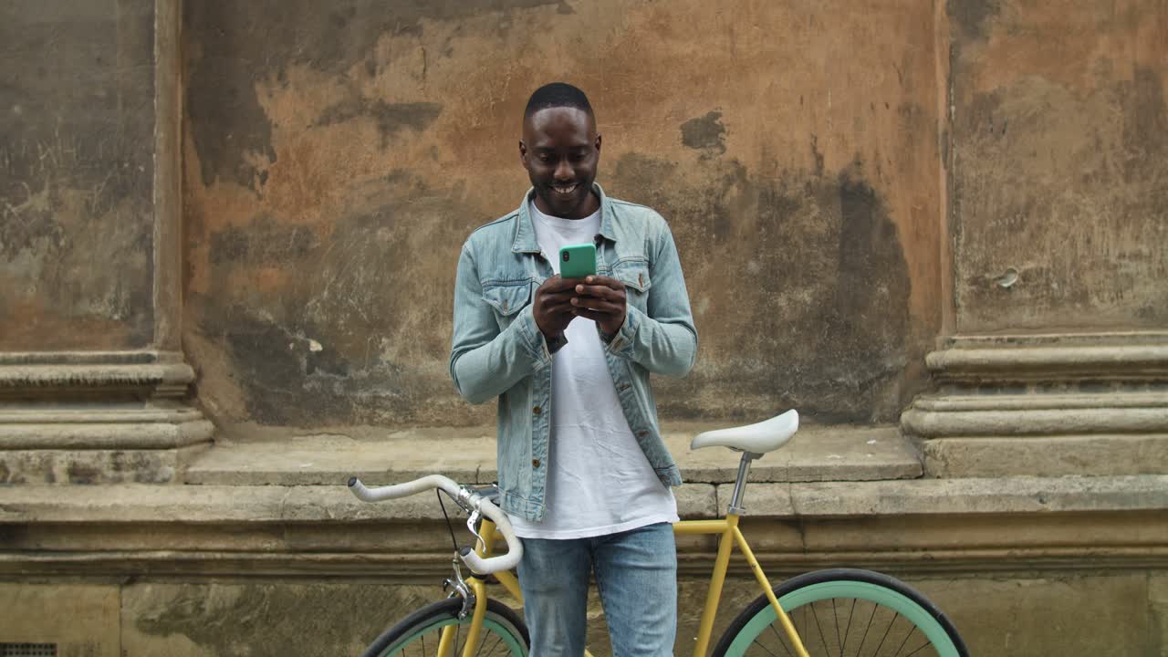 Mann mit Smartphone neben einem Fahrrad in einer städtischen Straße