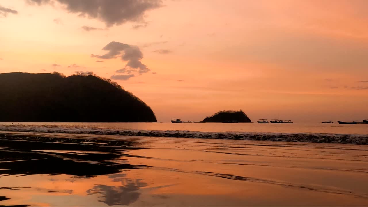 Bellissimo tramonto su una spiaggia sabbiosa e piccole onde oceaniche in Costa Rica, ora d'oro, paradiso tropicale