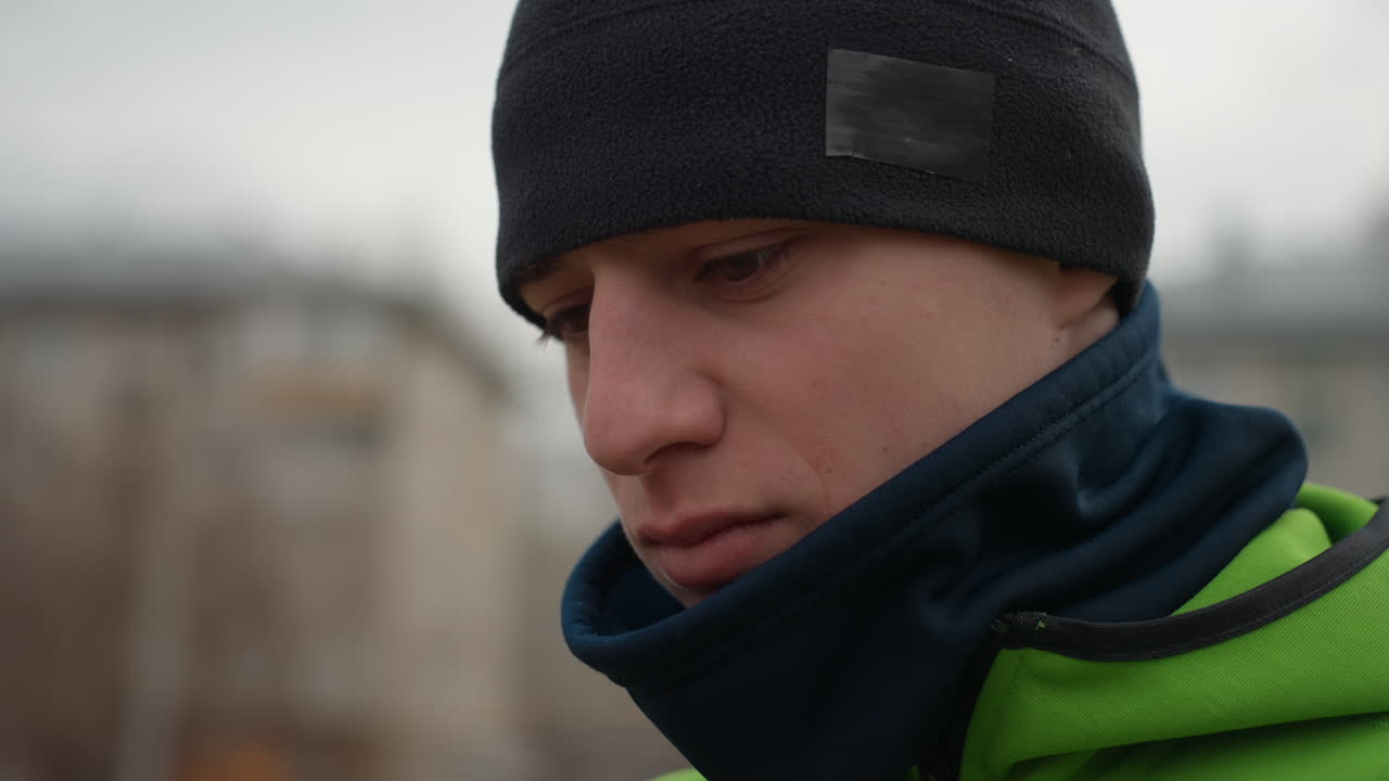 Un hombre de ciudad preparándose para un viaje, escena de un paso de peatones con un hombre ajustándose un gorro con ropa de invierno, un viajero urbano asegurándose de que la bufanda y la chaqueta estén bien puestas antes de salir con tiempo frío