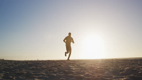 Hombre-Afroamericano-Corriendo-En-La-Playa,-Haciendo-Ejercicio-Al-Aire-Libre-En-La-Playa-Por-La-Noche