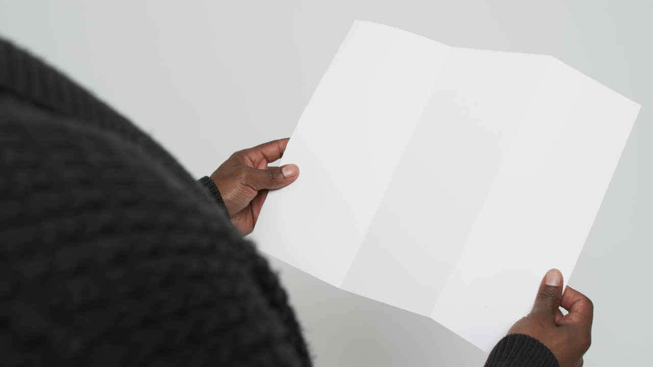 Video of hands of african american man holding blank page, copy space on white background