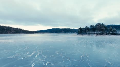 flying over the icy lake - frozen lake of omundvatnet in winter in indre fosen, trondelag, norway