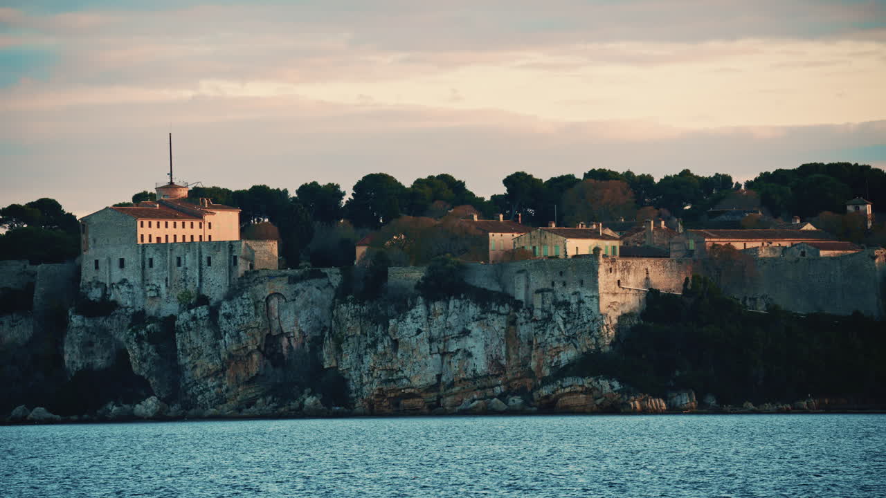 Udsigt over roligt middelhavsvand foran det historiske Fort Carre i Antibes