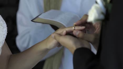 groom placing ring on brides finger in front of priest