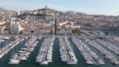 drone shot of marseille, france, yachts and sailboats in old city port, coastal traffic and cityscape skyline