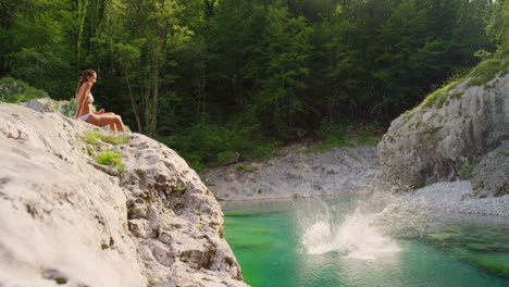 excited young woman jumping into a lake