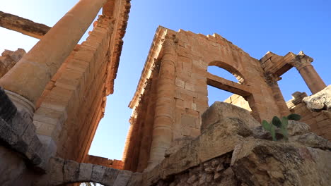 Antiguas-Ruinas-Romanas-Iluminadas-Por-El-Sol-De-Sbeitla-Contra-Un-Cielo-Azul-Claro-En-Túnez,-Vista-De-ángulo-Bajo