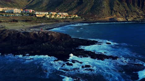 High-angle-shot-over-beautiful-waves-along-the-rocky-shoreline-in-Tenerife-island,-Spain-during-evening-time