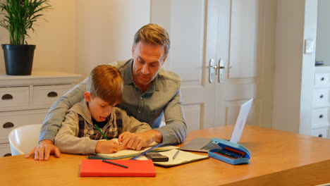 front view of young caucasian father helping son with homework at table in a comfortable home 4k