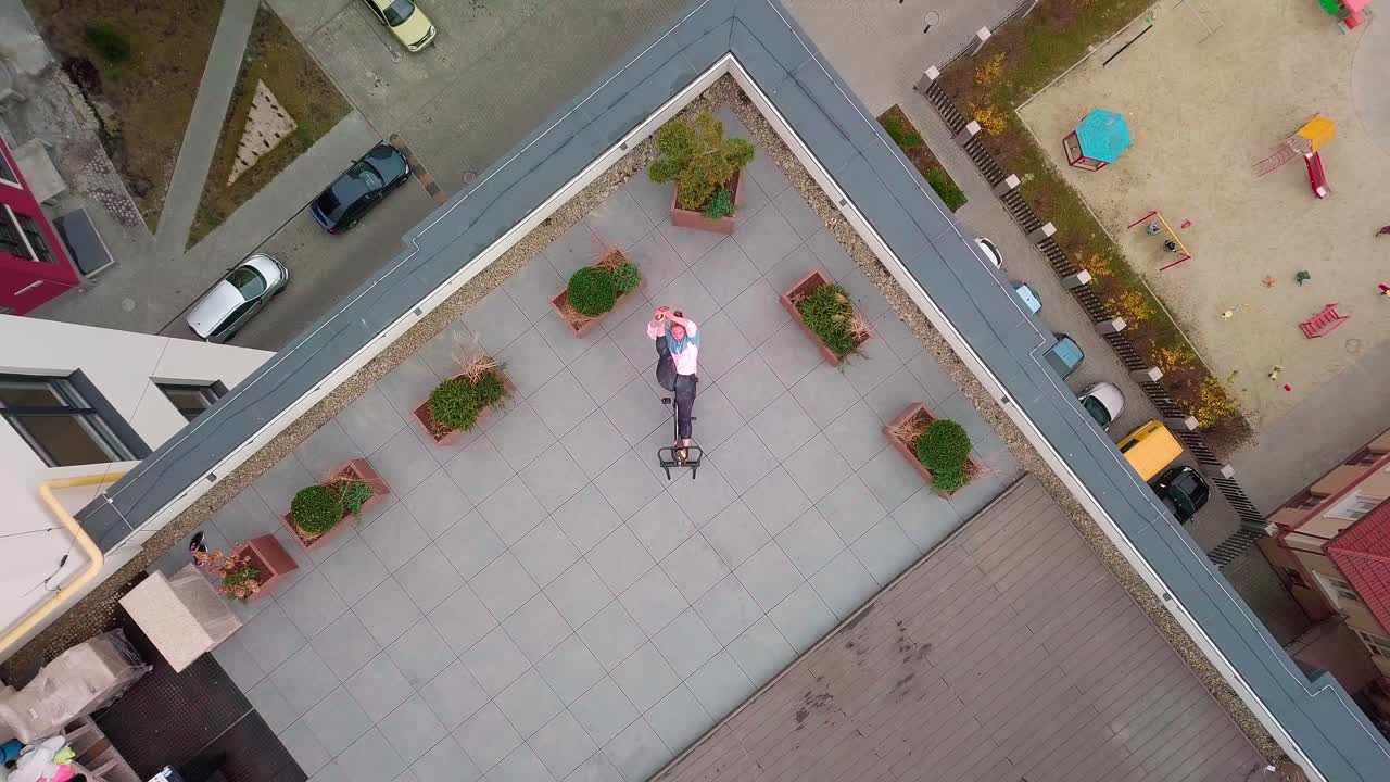 Athletic woman makes twine training routine on spinning stationary bike on house roof weight loss