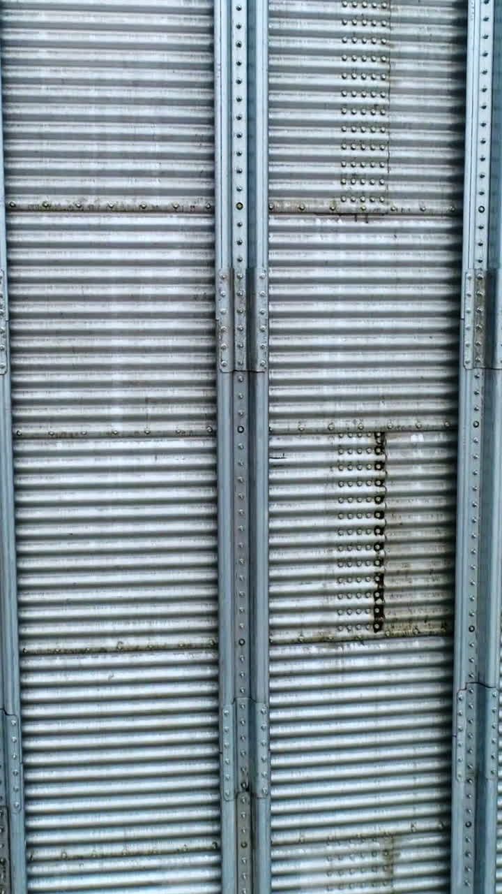 Silver metal sheathing of a modern elevator tank. Close up. Slow motion near the surface of silo cistern. Vertical video