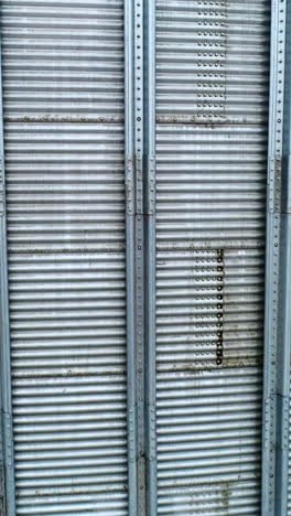 silver metal sheathing of a modern elevator tank. close up. slow motion near the surface of silo cistern. vertical video