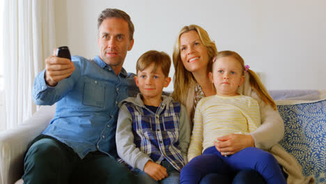 Front-view-of-Caucasian-family-sitting-on-the-couch-and-watching-television-in-a-comfortable-home-4k