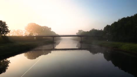 misty sunrise over a canal with bridge