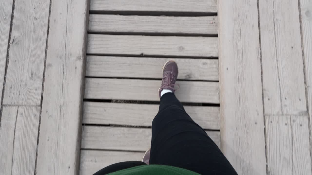 Woman hiker walking on a wooden bridge path