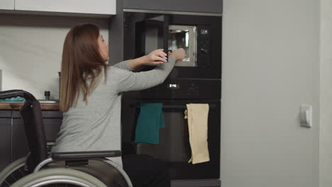 woman in wheelchair takes out plate with food from microwave