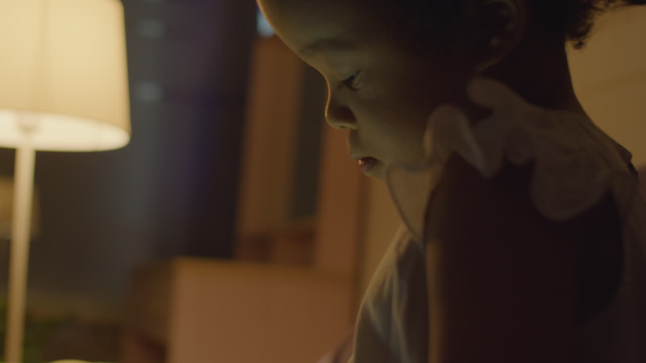 Little Asian Girl Using Digital Tablet in Evening on Bed