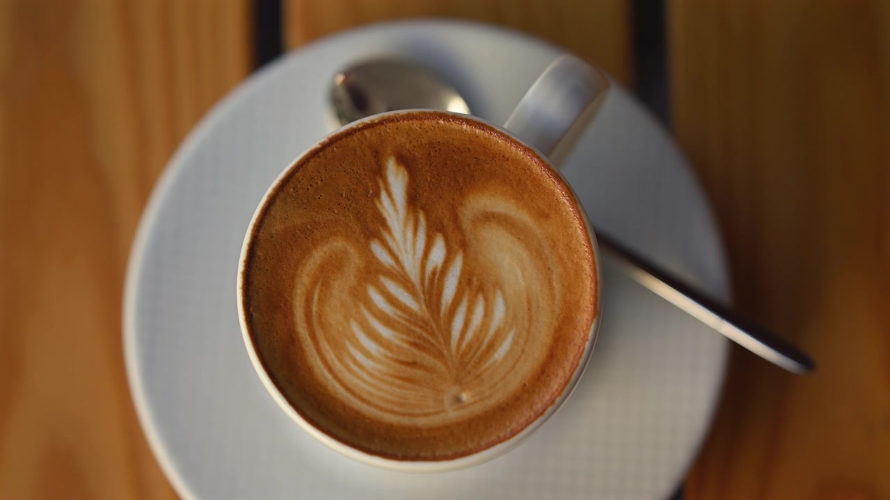 Latte macchiato appena preparato servito in una tazza di ceramica con un'elegante latte art a forma di foglia su schiuma cremosa