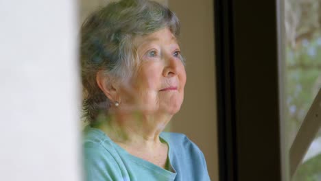 Senior-woman-looking-through-the-window-4k