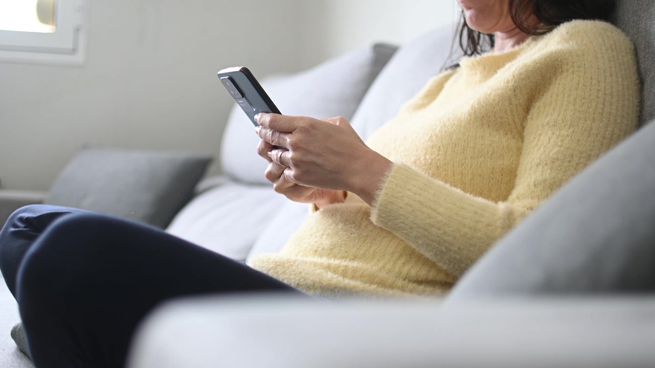 Detailní záběr ženy píšící na chytrém telefonu doma