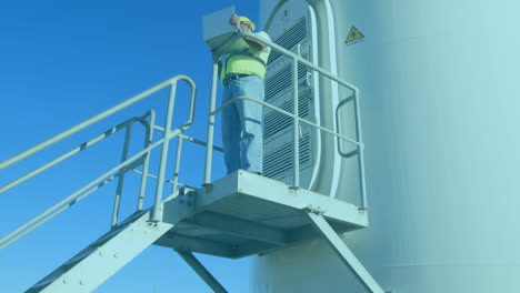 animation of statistical data processing against male engineer using laptop near a windmill