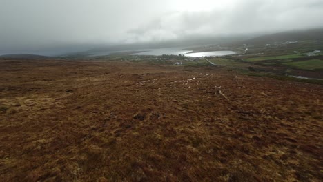 drone fpv volando rápidamente por una colina hacia un pueblo cerca del mar en irlanda