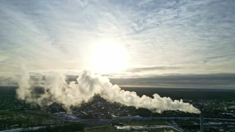 steam coming from a smokestack at a district heating complex - aerial view at sunset