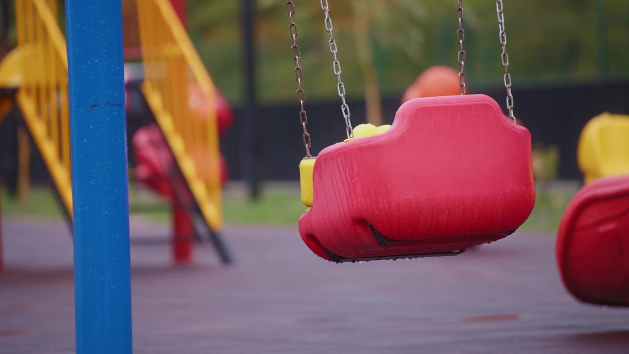 Altalena rossa bagnata su parco giochi vuoto