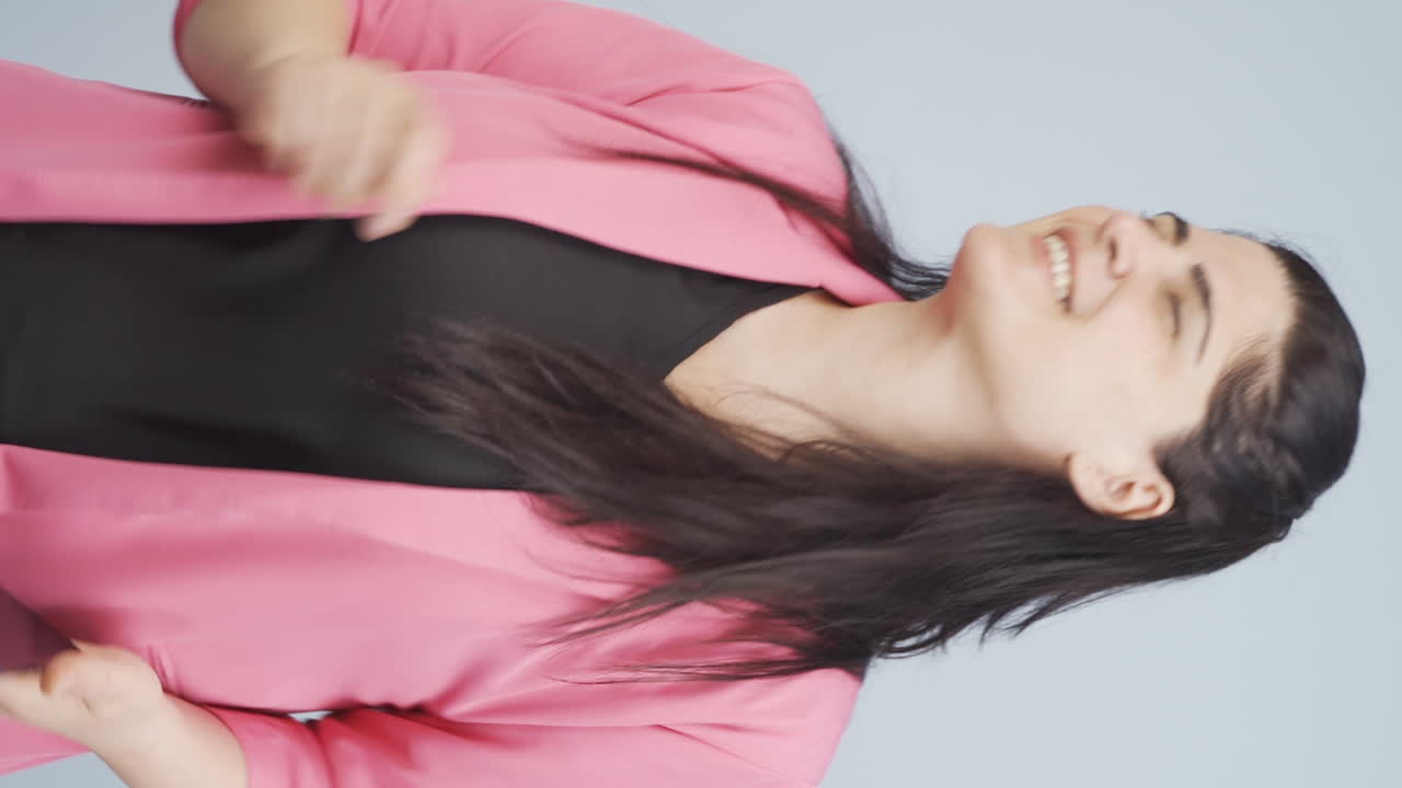 손에  ⁇ 드폰을 들고 춤추는 사업가 여성의 수직 비디오.