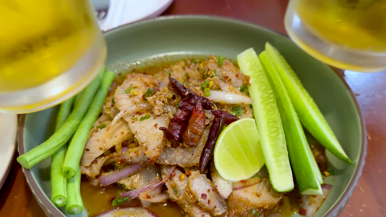 신선한 맥주와 함께 매운 태국 돼지고기를 즐기고 있습니다.