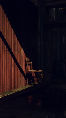 a wooden chair stands alone against a rusty metal wall, bathed in the soft glow of sunlight.