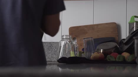 man drying washed glasses and plates then placing them back in kitchen cabinet - medium shot