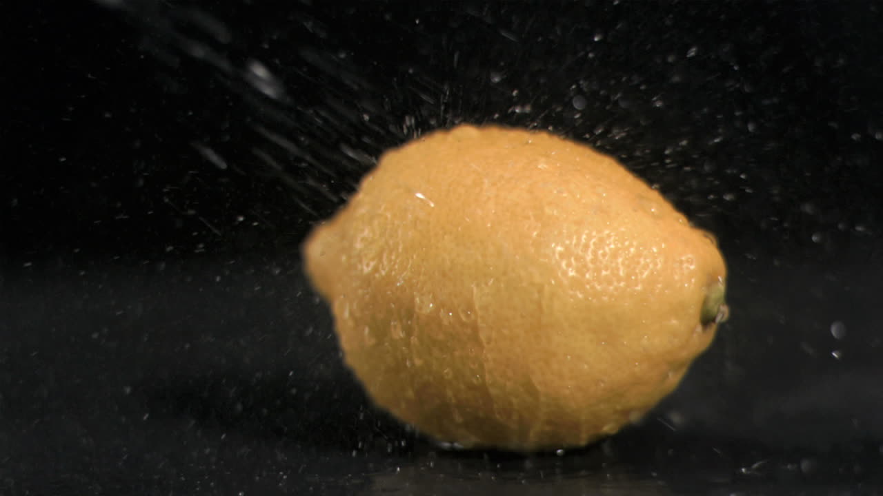 Water sprayed on lemon in super slow motion