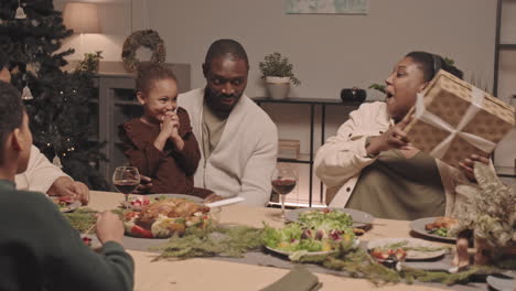 a black family celebrates christmas together with a gift giving