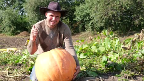 farmer young man in work clothes and hat on his head holding a pumpkin in his hands farmer young man in work clothes and hat on his head holding a pumpkin in his hands harvest season organically pure vegetables from the garden