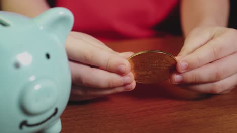 the child puts a bitcoin gold coin in a piggy bank