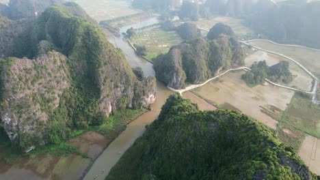 Drone-Volando-Sobre-Las-Cumbres-Escarpadas-De-La-Garganta-De-Piedra-Caliza-Que-Revela-El-Río-Ngo-Dong-Y-El-Campo-De-Arroz-Agrícola-En-Ninh-Binh-Vietnam-En-La-Puesta-De-Sol-De-La-Hora-Dorada