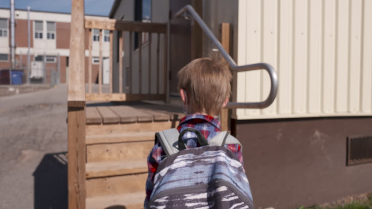 un niño lindo entrando a la escuela con una máscara facial