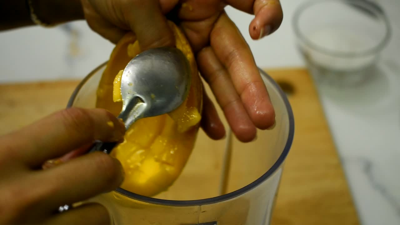 close up of a chpped mango putting into a mixer grinder jar