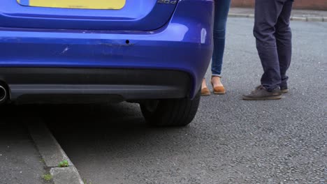 el extremo trasero del coche dañado en el paragolpes azul el hombre y la mujer discuten el área del accidente