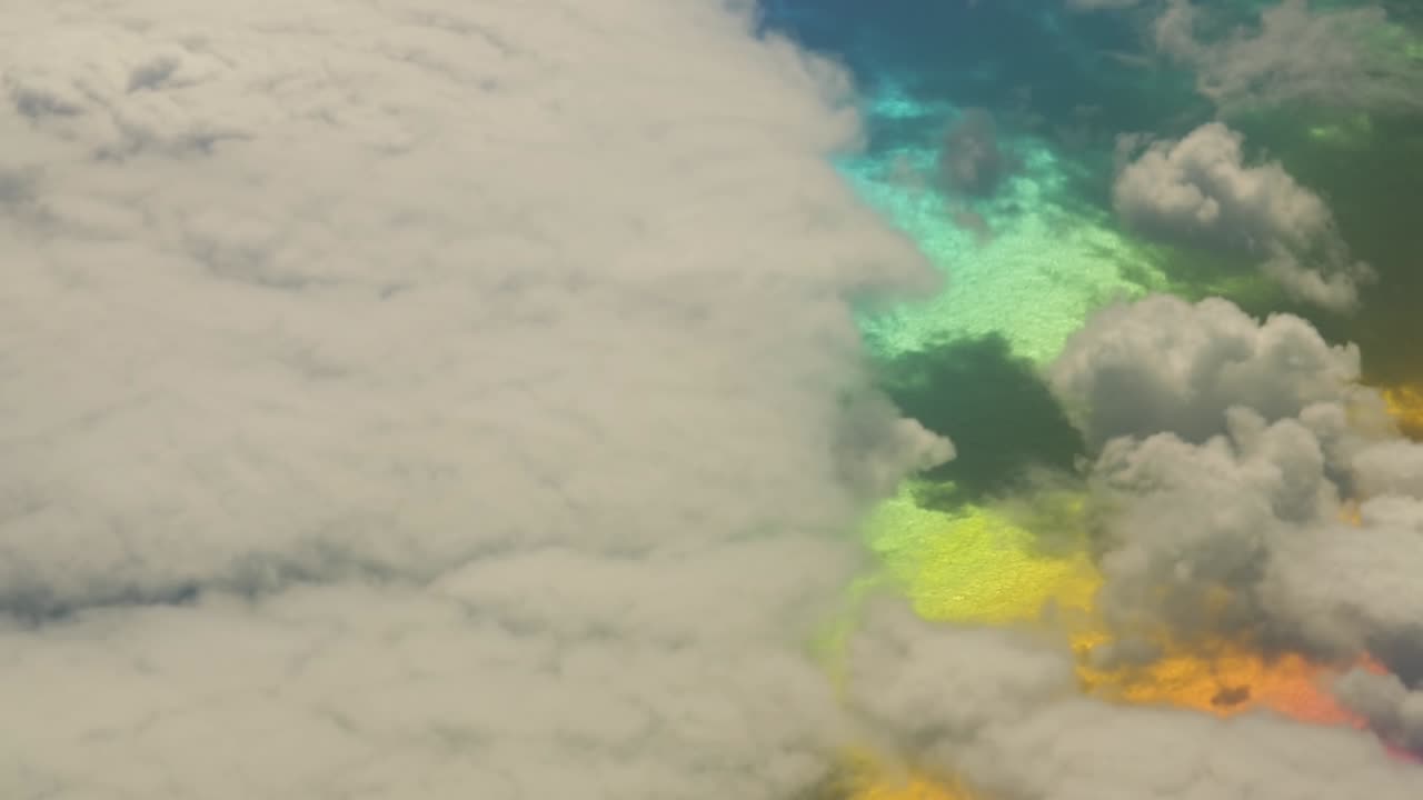 Happy unreal fantasy colors on water surface in the atlantic ocean from above with white clouds
