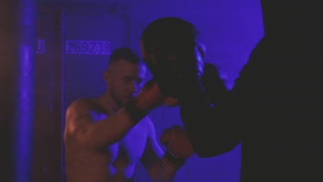 boxeador sin camisa se calienta golpeando los guantes de combate