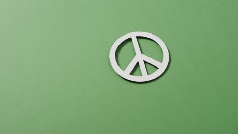 close up of white peace sign and copy space on green background