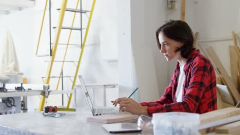 Carpenter-using-laptop-while-writing-on-notepad-4k